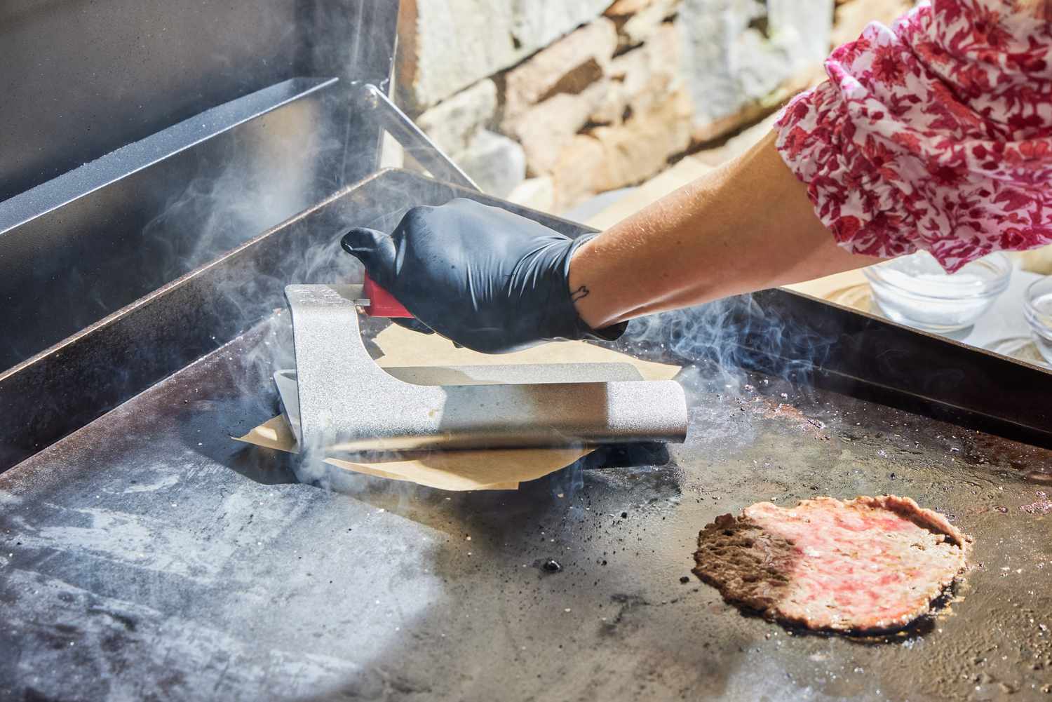 A person cooks smashburgers on the Weber 36 Inch Gas Griddle