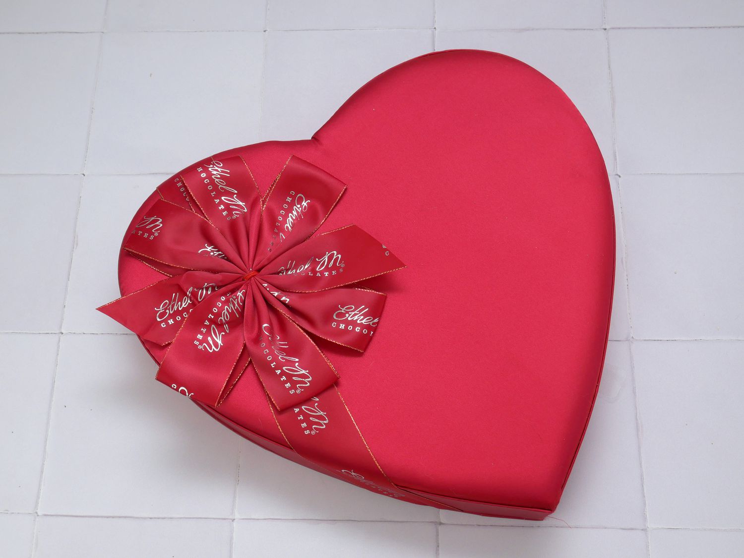 the ethel m heart-shaped box of chocolates on a white tile surface