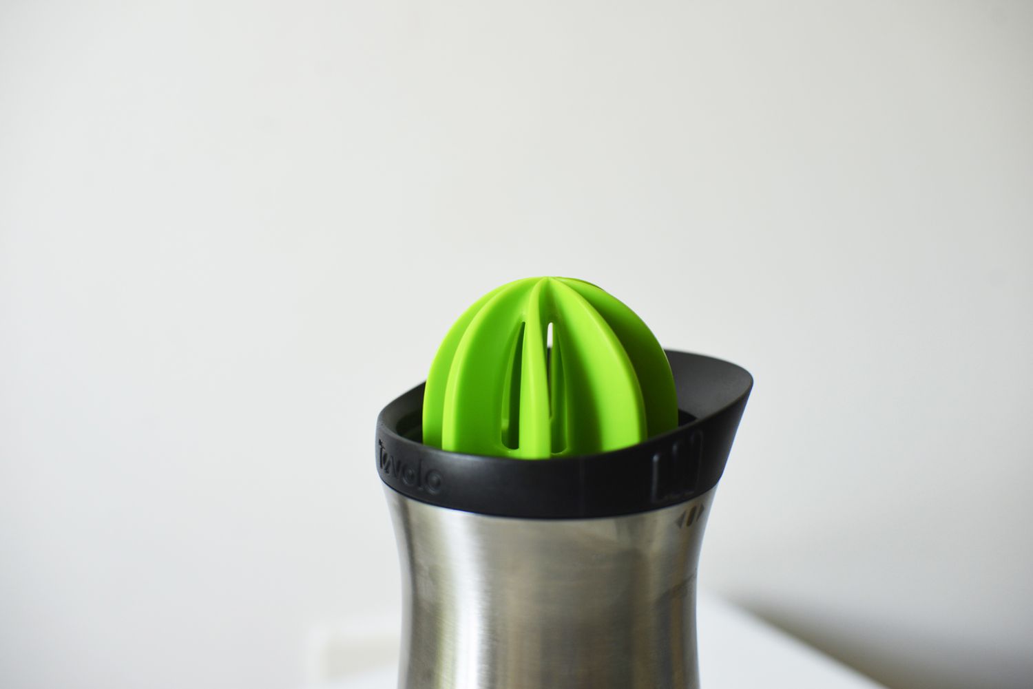 A closeup of a cobbler shaker with a built-in citrus juicer top