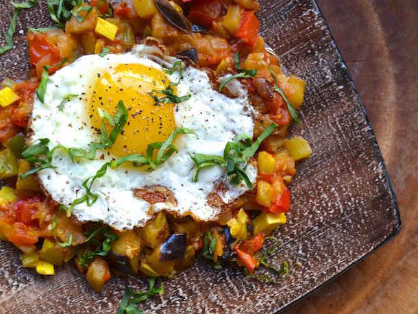 Ratatouille with a fried egg on top, garnished with chopped parsley.