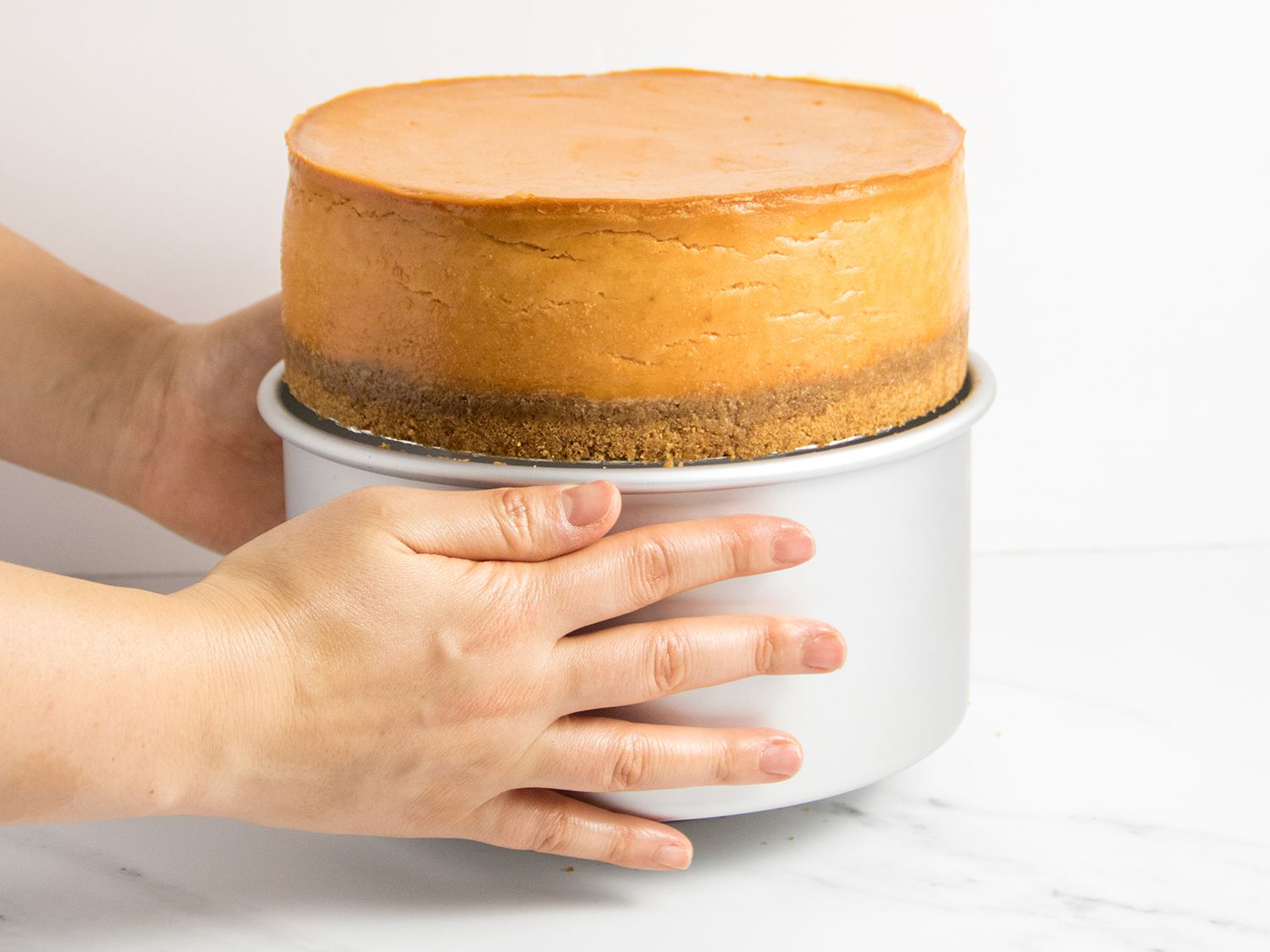 Removing the cake pan from the cheesecake.