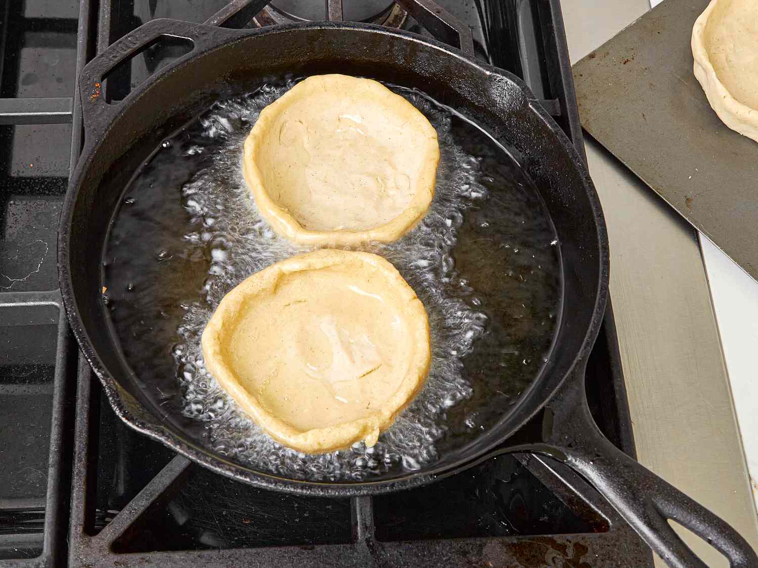 Two sopes frying in a cast iron skillet.