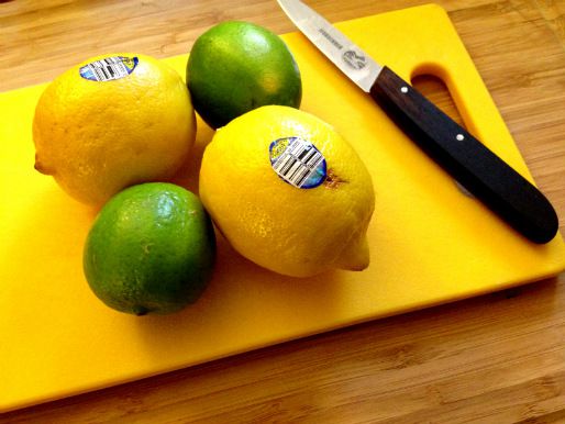 Whole lemons and limes on a cutting board.