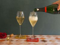 a person pouring champagne into the riedel glasses