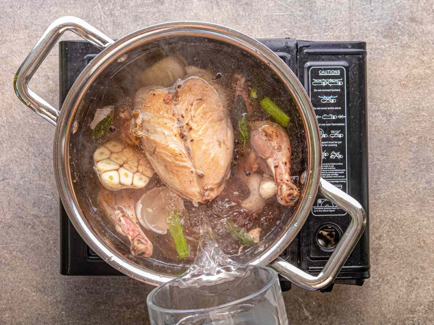 A pot of chicken and vegetables being boiled photographed from above
