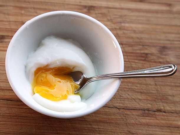 Spoon breaking open poached egg cooked sous vide