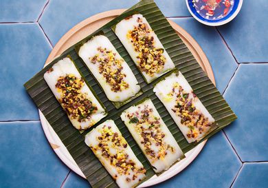 Overhead view of finished banh man on a banana leaf one a blue titled background