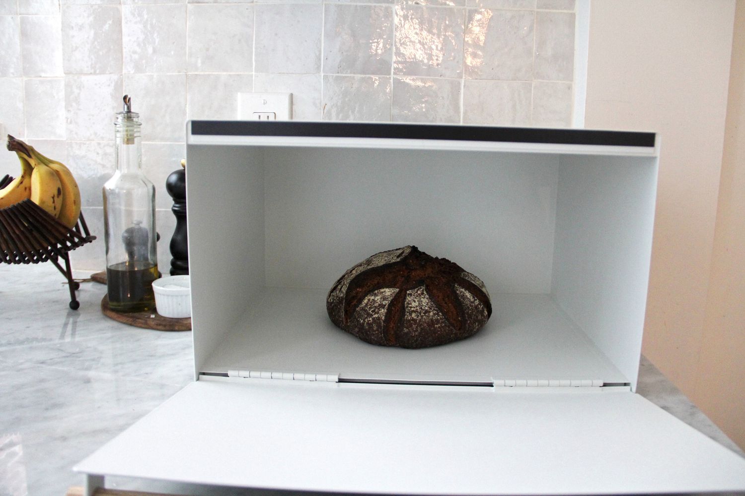 A bread box on a kitchen countertop with bread in it.