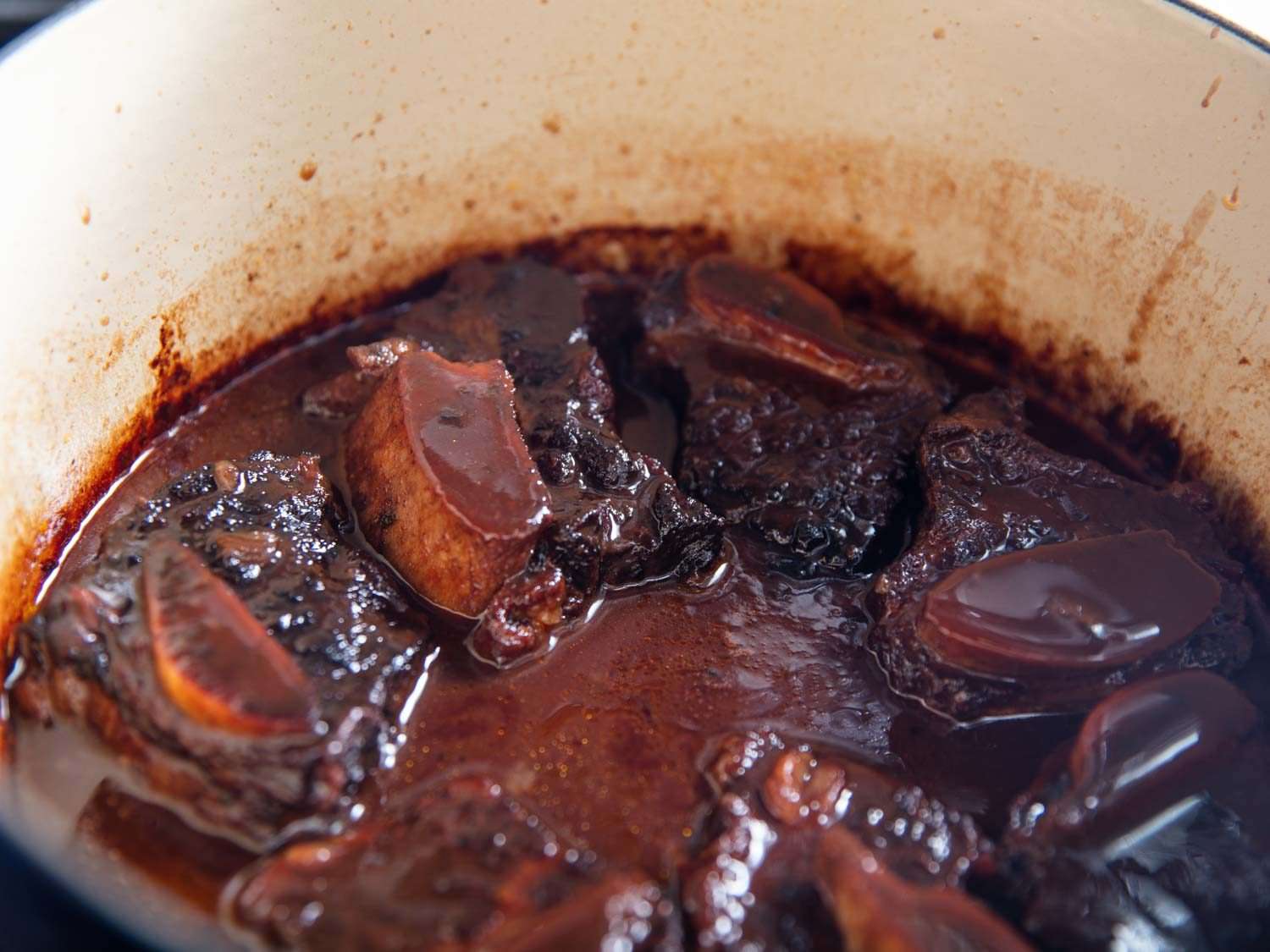 Braised beef short ribs in a Dutch oven with the finished red wine sauce