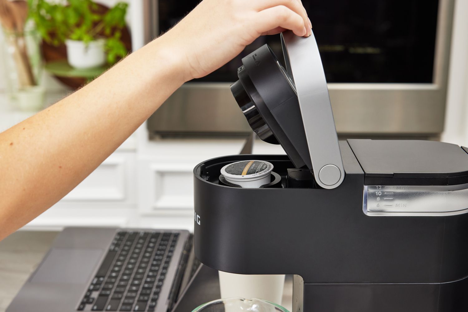 A hand closing the lid of a keurig machine