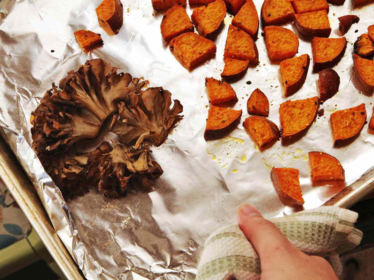 Roasted maitake mushroom and diced sweet potato on a foil-lined sheet pan for creamy vegan ramen toppings.