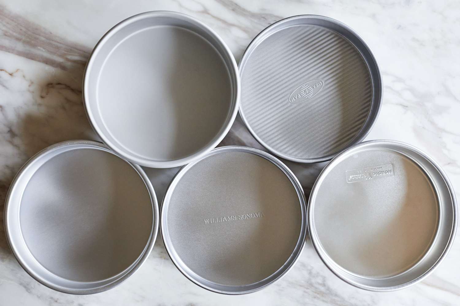 five cake pans on a marble kitchen countertop