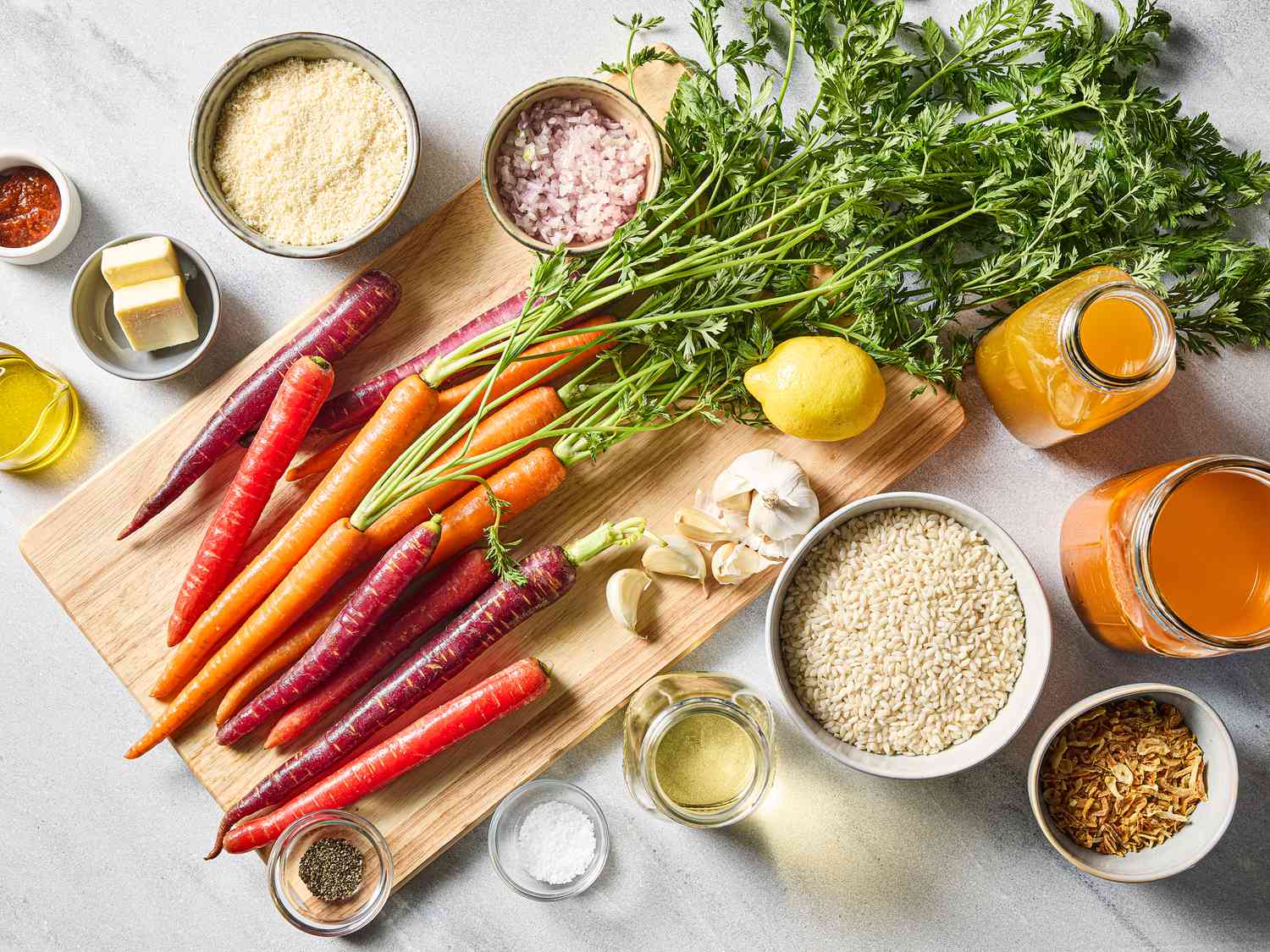 Ingredients arranged for carrot risotto preparation on a cutting board with various vegetables and cooking items