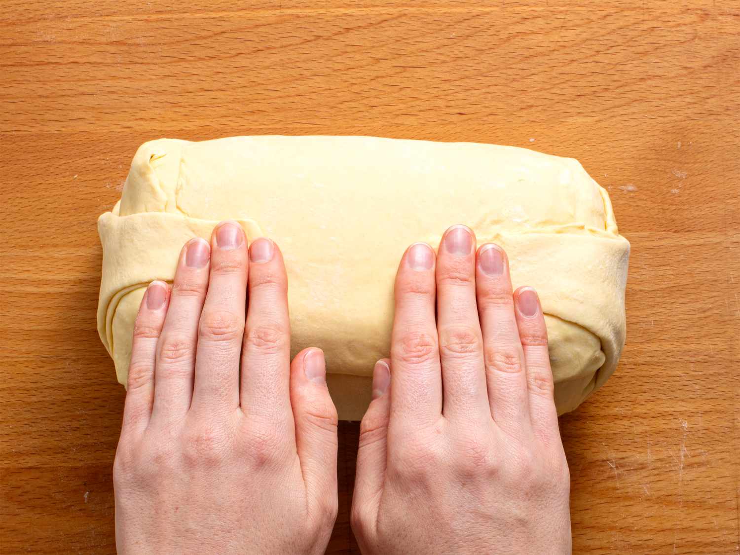 The ends of the puff pastry being flattened against the seam on the beef wellington.
