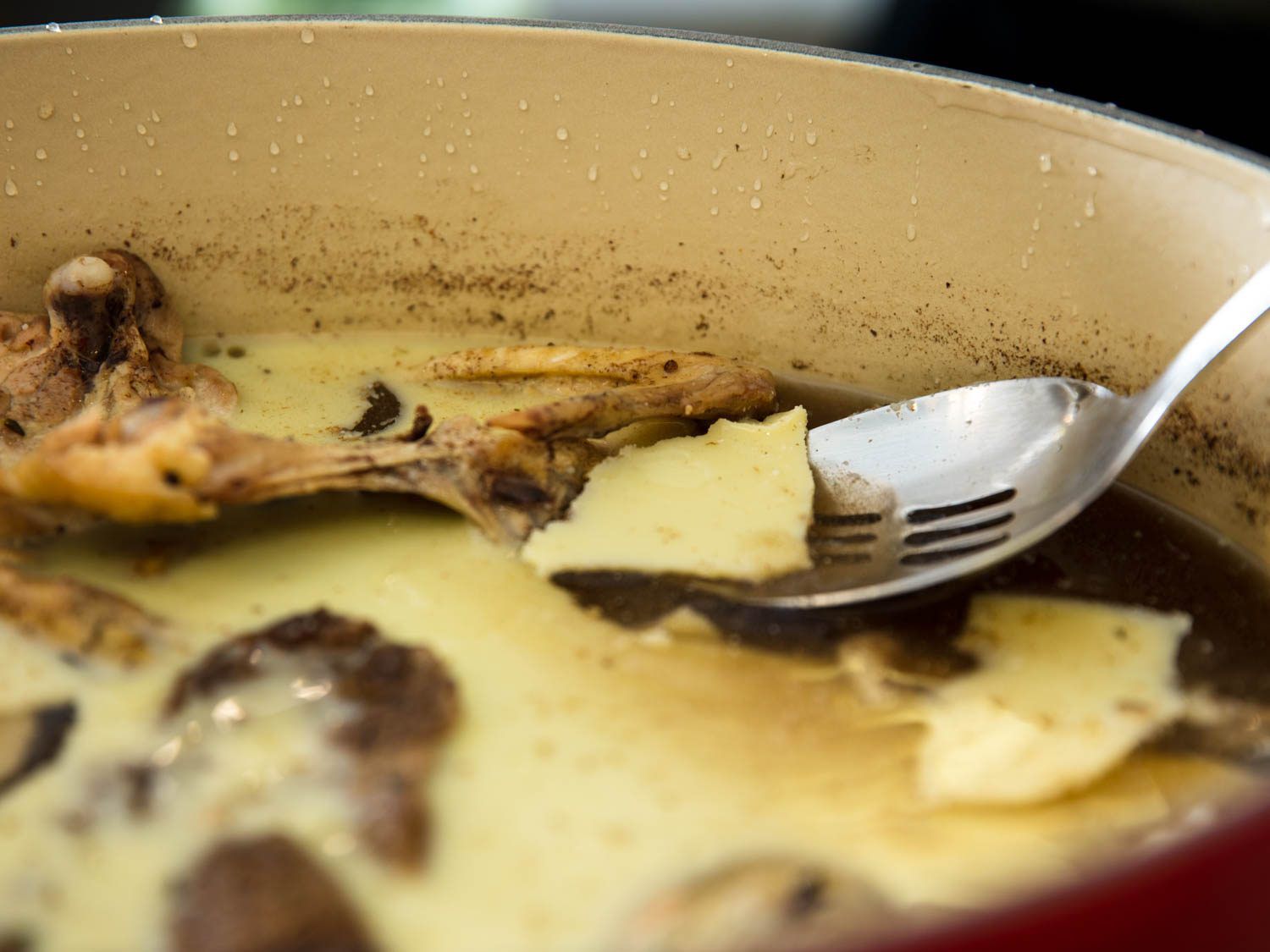 skimming solidified fat off surface of cold bollito misto