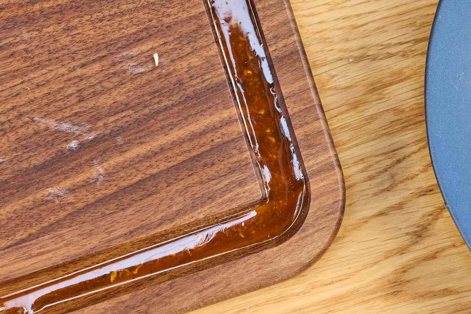 Closeup of a Virginia Boys Kitchens Walnut Wood Cutting Board with a grove partially filled with sauce or liquid