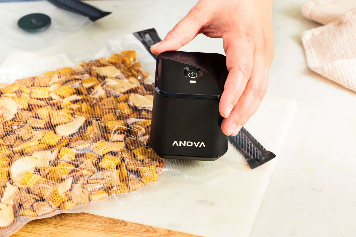 the anova handheld sealer with a bag of sealed chex mix 