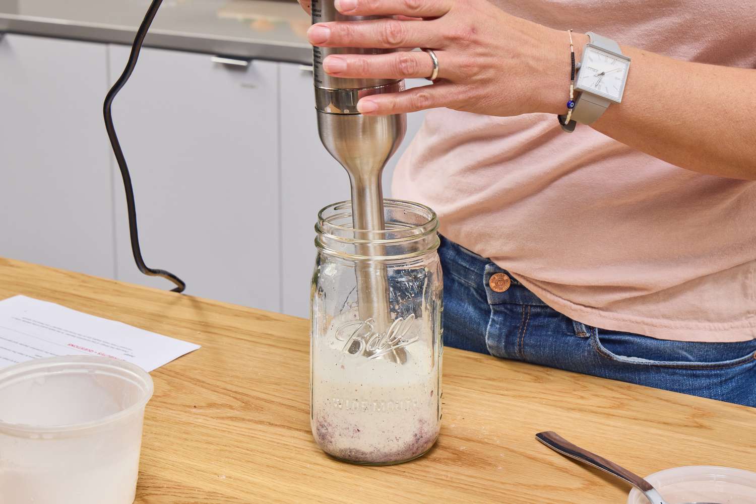 A person uses the Vitamix Immersion Blender inside a glass jar