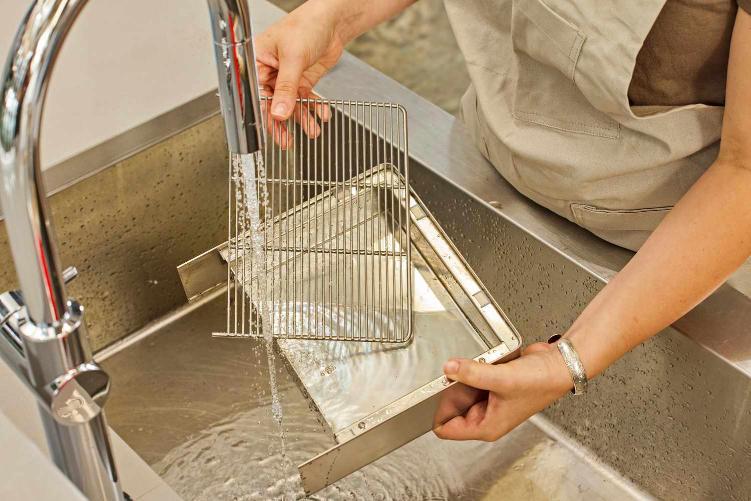 A person washing parts of the Lelit MaraX Espresso Machine PL62X-120 in a sink
