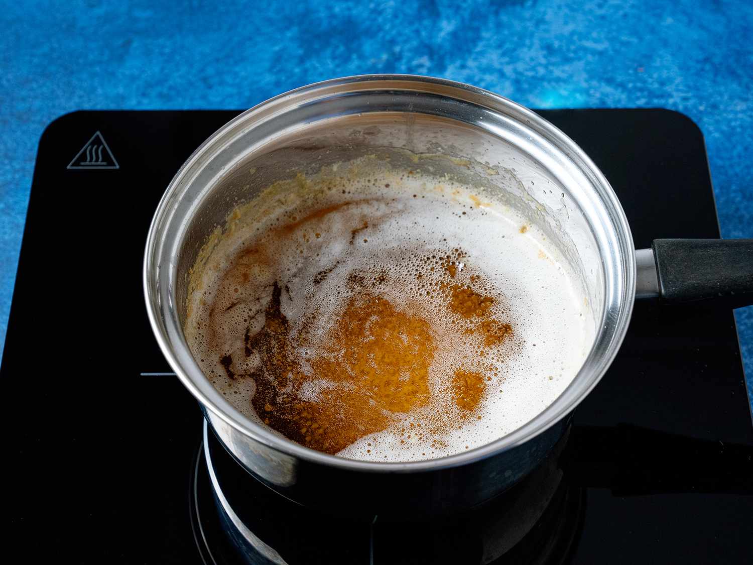 A pot of boiling butter with milk proteins sinking to the bottom of the pan
