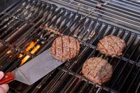 A close-up of a hand sliding a spatula under a patty on the Weber Spirit EP-435 Gas Grill