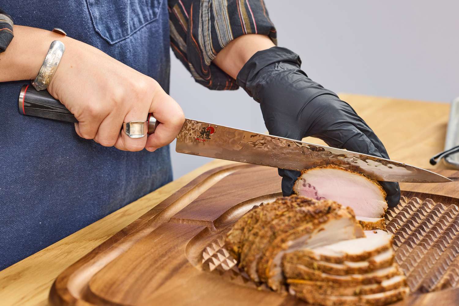 A person slices meat with the Miyabi Mizu SG2 9.5 Inch Slicing Knife