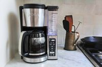 A Ninja CE251 12-Cup Coffee Brewer on a kitchen counter with utensils in the background