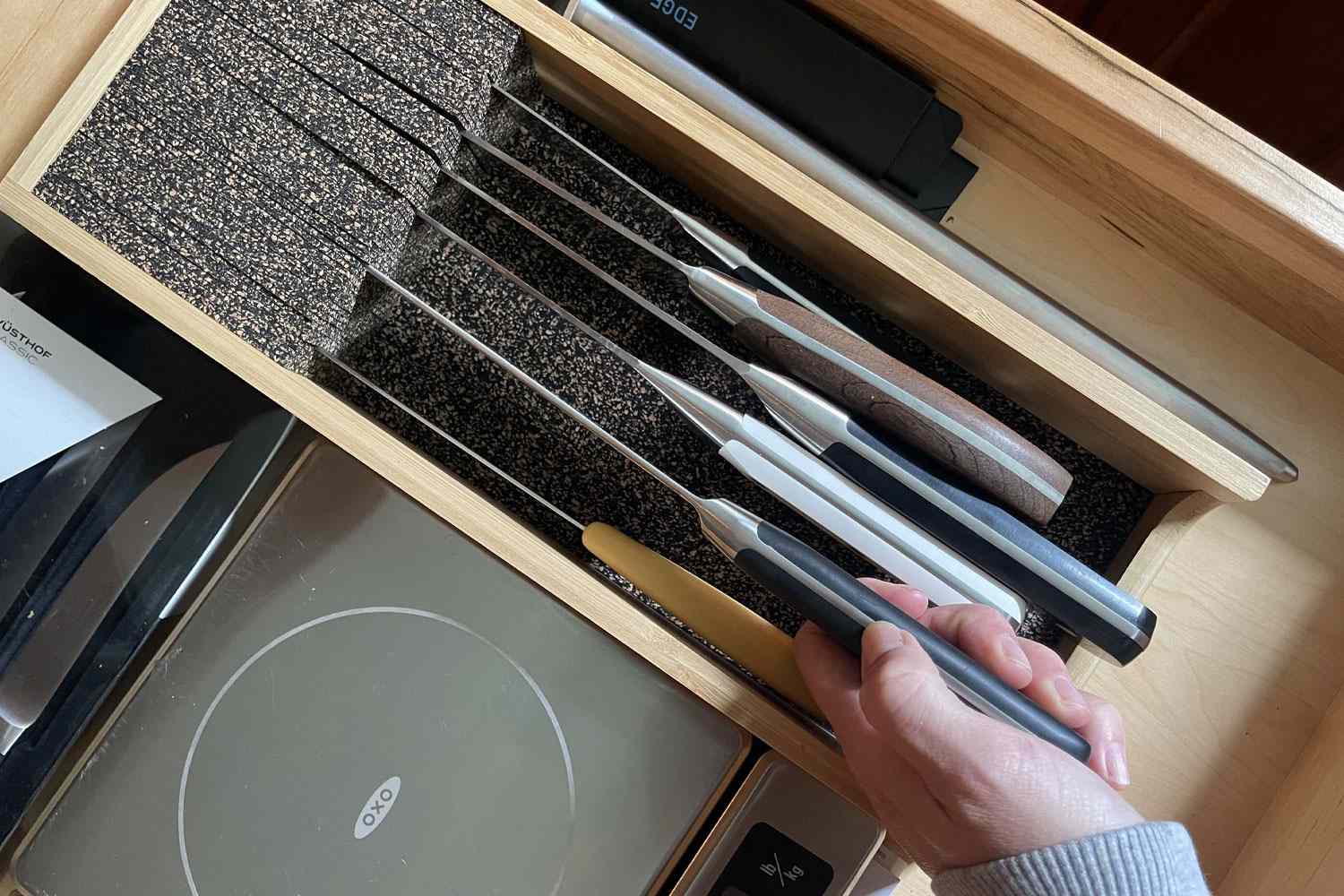 A hand pulling a knife out of the Knife Dock In-Drawer Knife Storage