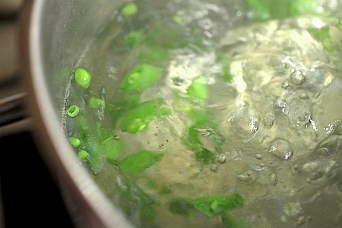 Peas being blanched in a pot of boiling water.