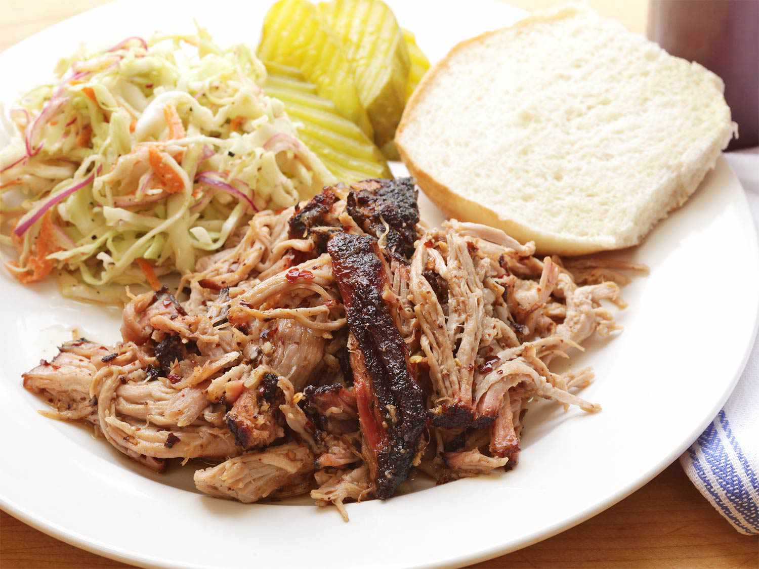 Shredded pork shoulder served with coleslaw, pickles, and a bun