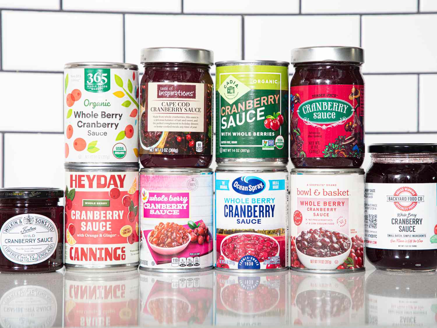 Several jars and cans of cranberry sauce arranged on a counter showcasing different brands and packaging styles