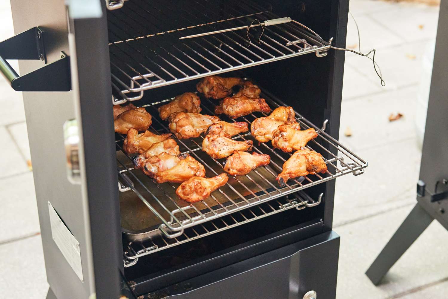 A closeup of a shelf of wings in the Cuisinart COS-244 Vertical Propane Smoker