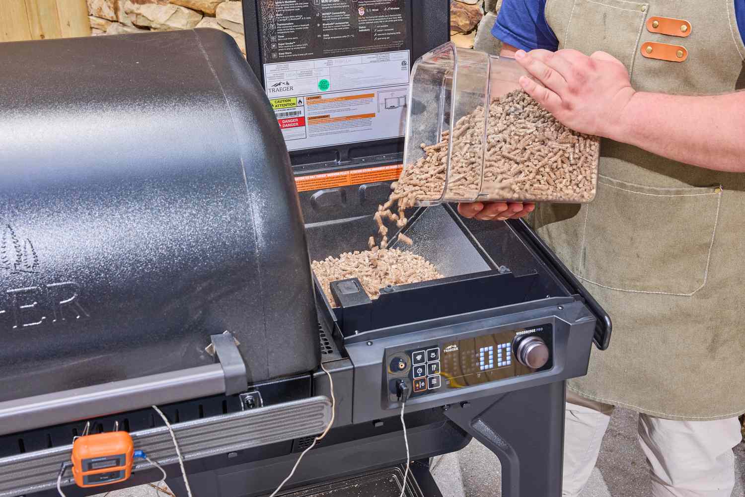 A person pours pellets into the Traeger Woodridge Pro