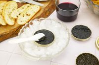 Island Creek Caviar Displayed on Table in Ice Bowl With Red Wine And Toasts