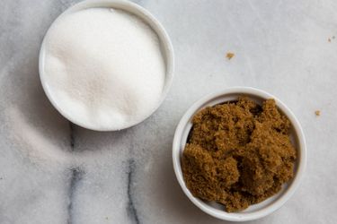 Overhead view of two ramekins filled with white and brown sugar, respectively.