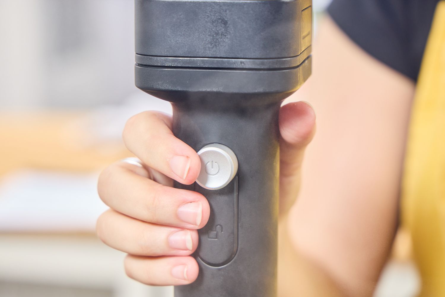 A person presses a button on the KitchenAid Go Cordless Hand Blender