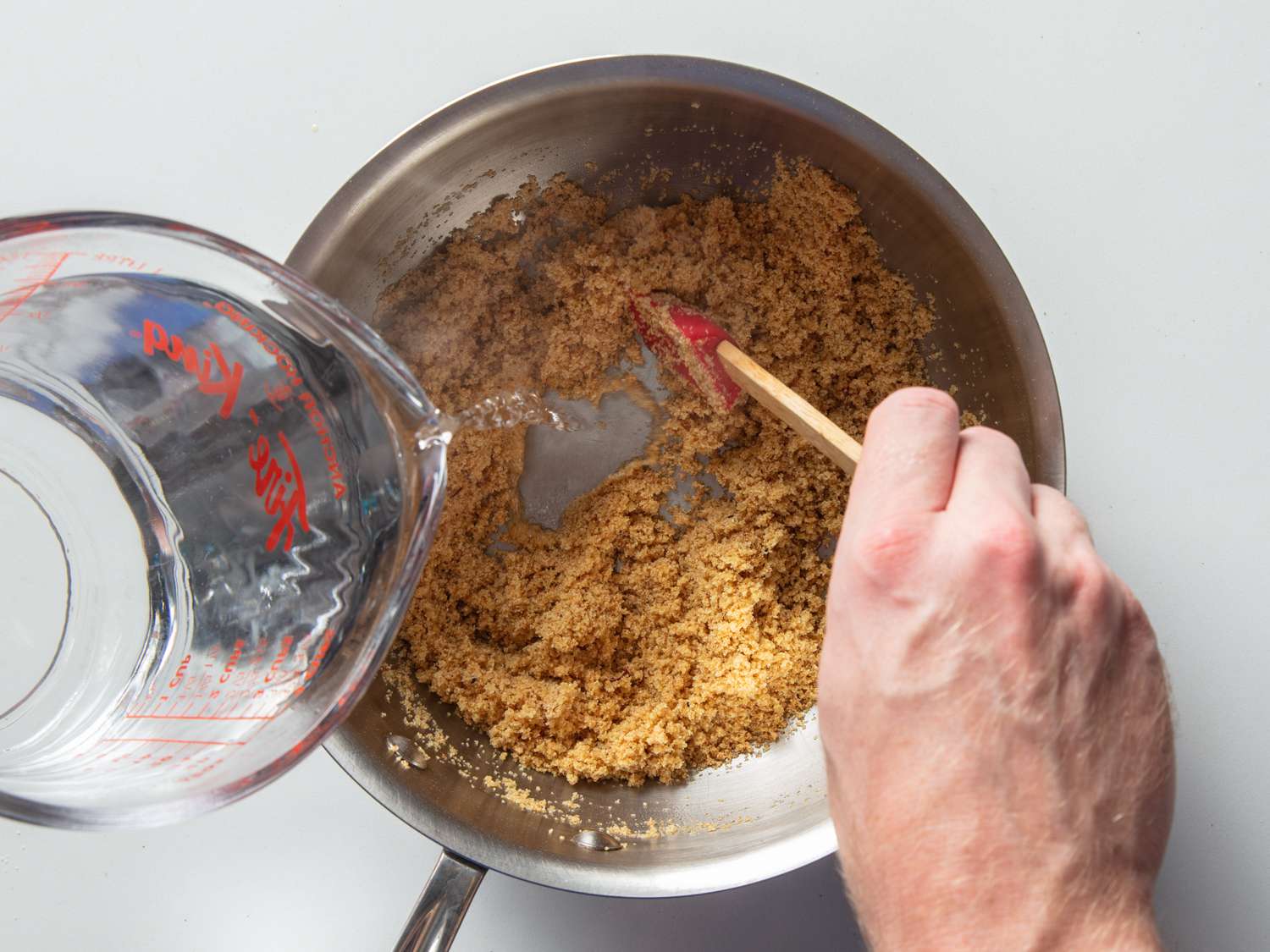 Boiling water being poured into a saucepan containing a mixture of semolina and ghee