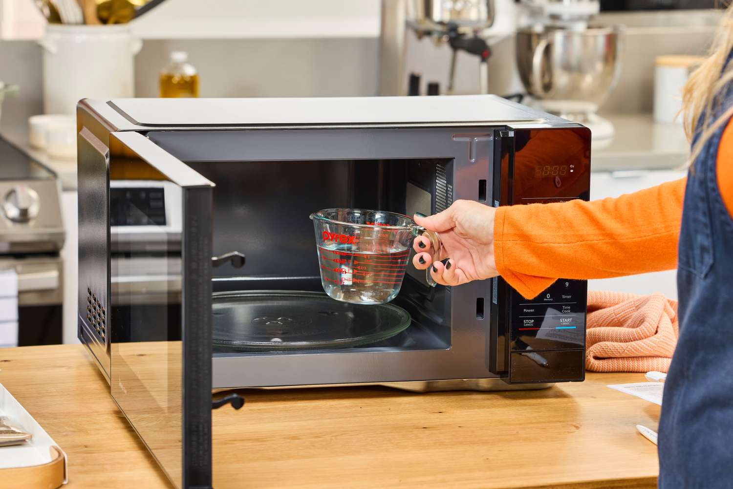 A person placing a cup of water into a Magic Chef 1.1 Microwave