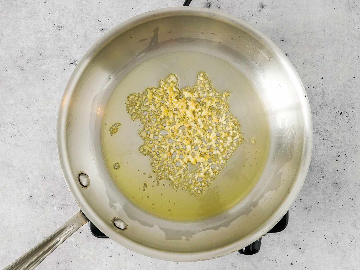 garlic simmering in oil in a skillet