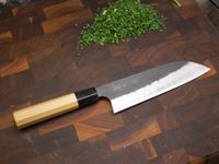 sakai kikumori santoku on a wooden cutting board
