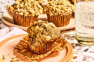 A tray and a plate of banana oatmeal muffins with a glass of sparkling water