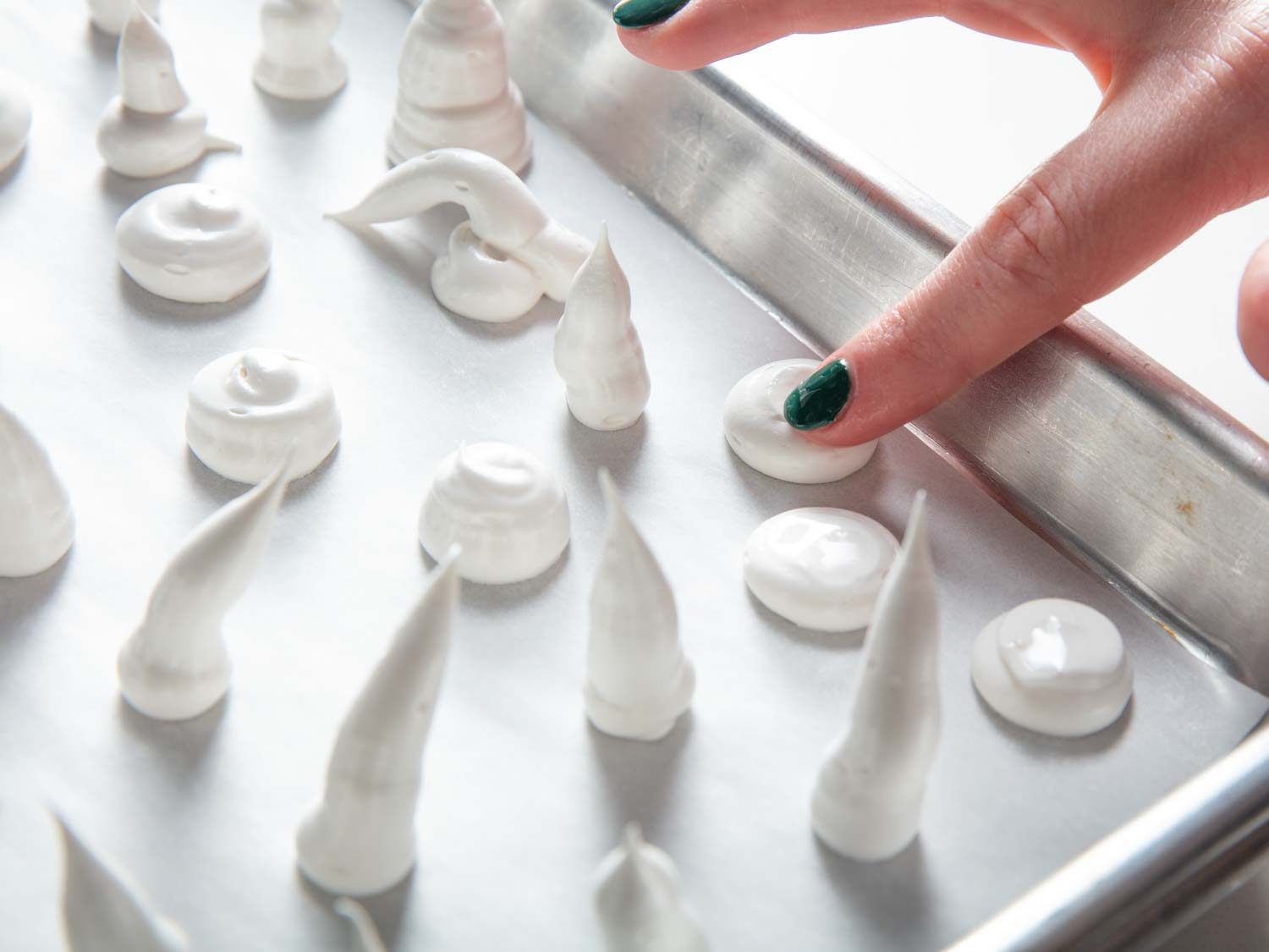 Smoothing the surface of a meringue mushroom cap with a wet fingertip