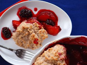 Closeup of blackberry-plum cobbler, served on a white plate from the baking dish.