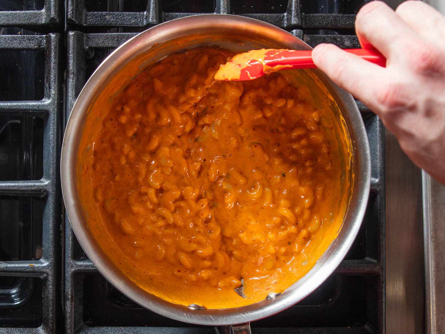 Emulsifying all the ingredients in stovetop 'nduja mac and cheese with a spatula. 