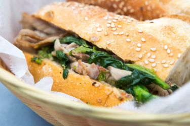 A roast pork sandwich in a basket lined with deli paper. 