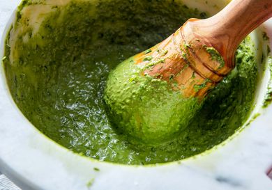 A classic Genovese-style pesto sauce made in a granite mortar with a wooden pestle.
