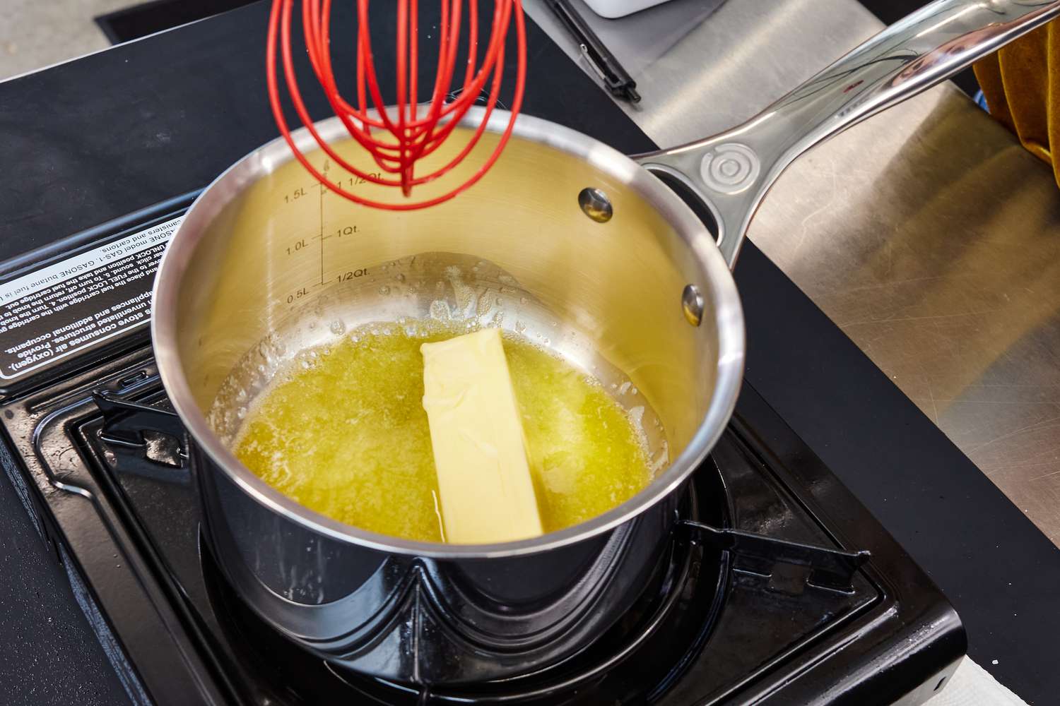 A chunk of butter melting in a saucepan on a stove