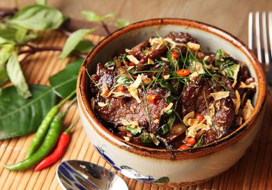 A ceramic bowl filled with Thai-style beef with basil and chiles.