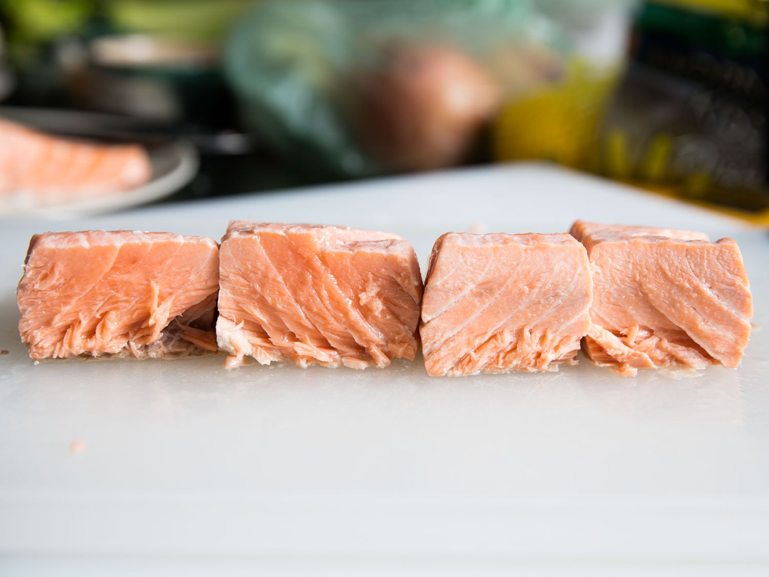 Four pieces of salmon fillet. The two on the left are noticeably pinker and moister looking than the two on the right.