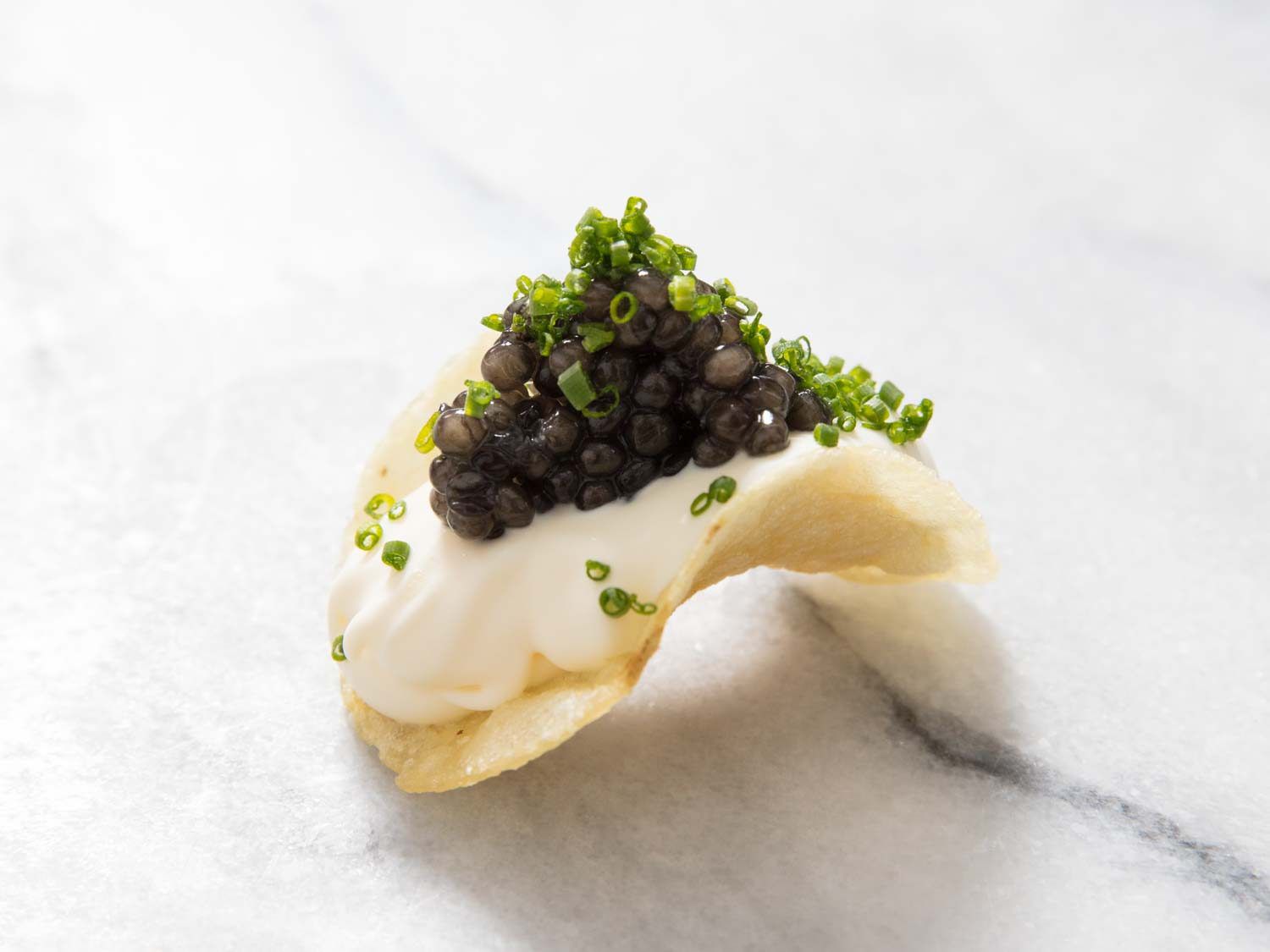 Caviar, crème fraîche, and chives on a potato chip